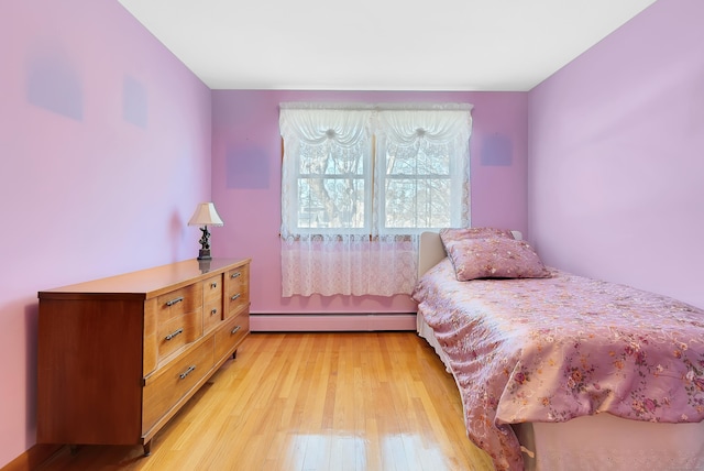 bedroom with light wood finished floors and a baseboard radiator