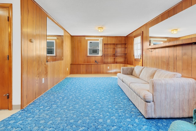 carpeted living room featuring wood walls and built in shelves