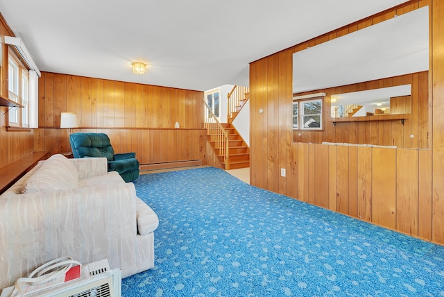 living area with stairway, carpet flooring, baseboard heating, and wooden walls