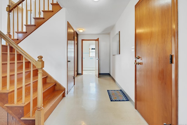 entryway featuring stairway, a baseboard heating unit, and baseboards