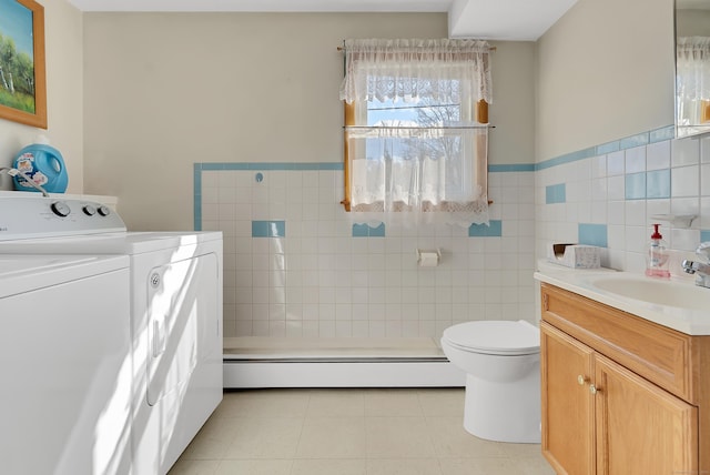 full bathroom with vanity, a baseboard radiator, tile walls, tile patterned floors, and washer and clothes dryer