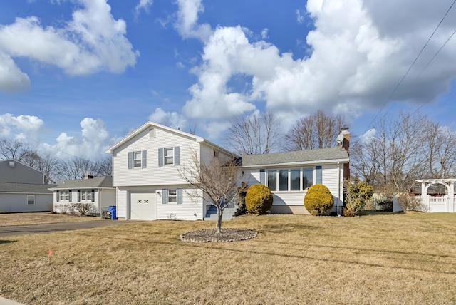 view of front of home with a front lawn, an attached garage, fence, and a chimney