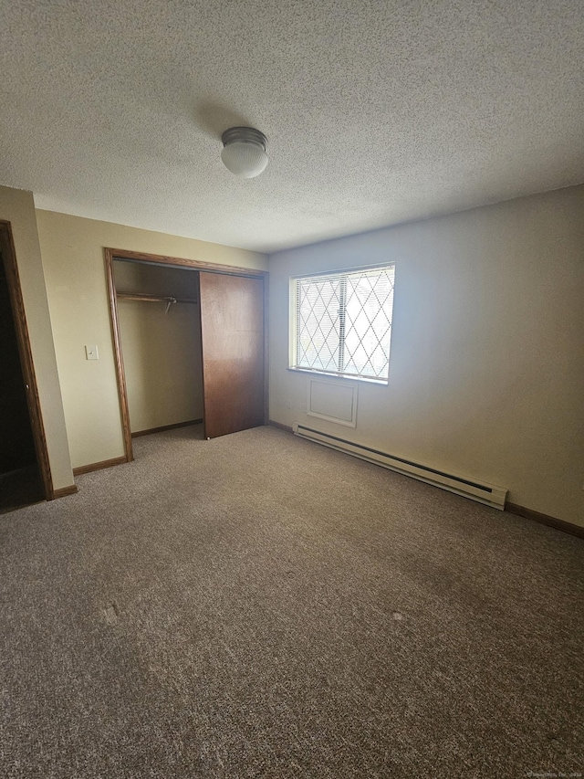 unfurnished bedroom featuring a baseboard heating unit, a textured ceiling, a closet, carpet flooring, and baseboards