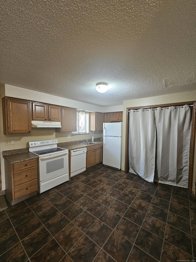 kitchen featuring a sink, under cabinet range hood, dark countertops, a textured ceiling, and white appliances