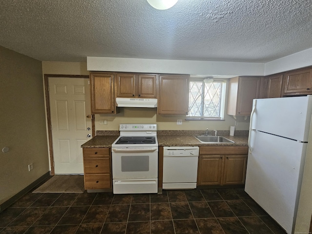 kitchen with under cabinet range hood, a sink, dark countertops, white appliances, and baseboards