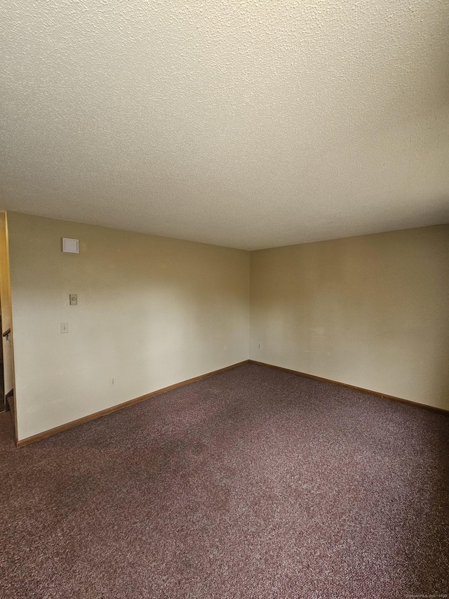 carpeted spare room featuring baseboards and a textured ceiling