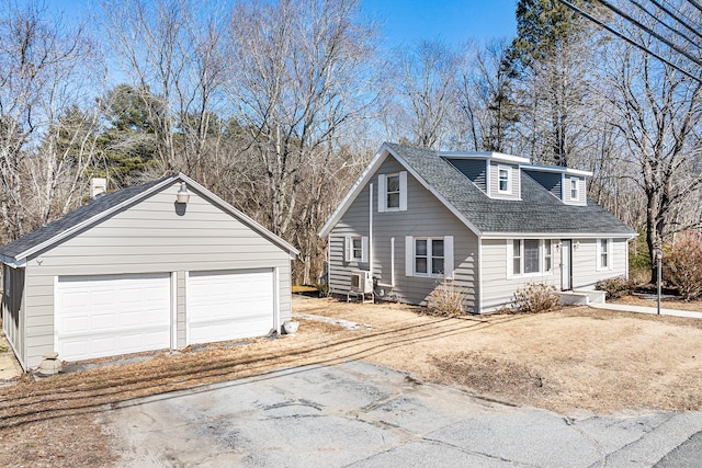 exterior space with a detached garage, an outdoor structure, and a shingled roof