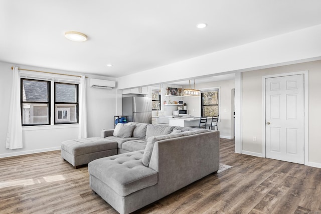 living area with recessed lighting, baseboards, an AC wall unit, and wood finished floors