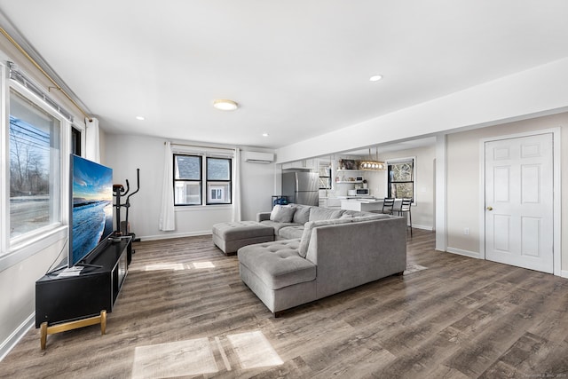 living area with recessed lighting, baseboards, an AC wall unit, and wood finished floors