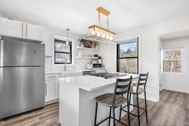 kitchen featuring a kitchen island, a breakfast bar, freestanding refrigerator, white cabinetry, and light wood-type flooring