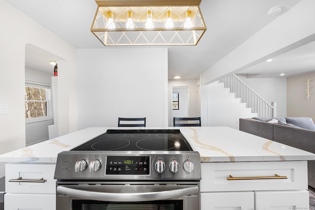 kitchen featuring light stone counters, open floor plan, stainless steel range with electric cooktop, recessed lighting, and white cabinets