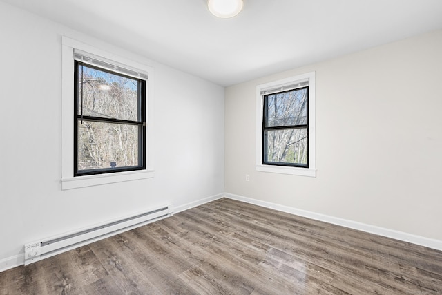 unfurnished room with wood finished floors, baseboards, and a baseboard radiator