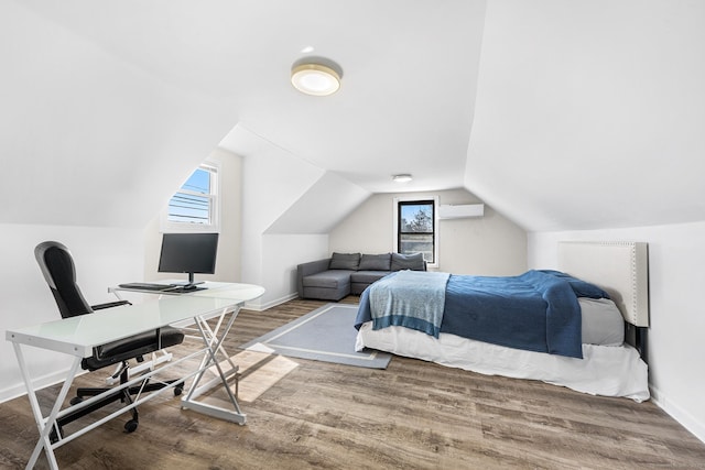 bedroom featuring vaulted ceiling, multiple windows, baseboards, and wood finished floors