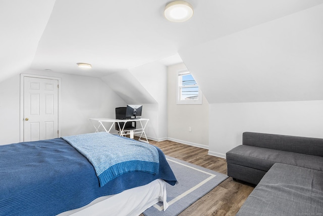 bedroom featuring baseboards, lofted ceiling, and wood finished floors