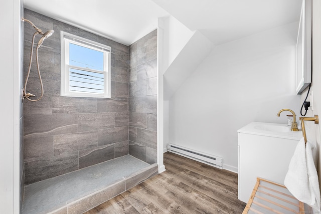 full bath with vanity, wood finished floors, baseboard heating, and tiled shower