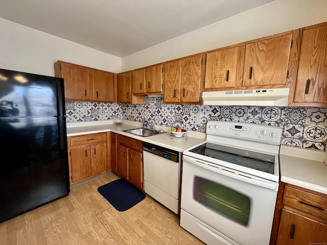 kitchen featuring white appliances, a sink, light countertops, under cabinet range hood, and brown cabinets