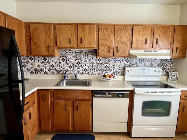 kitchen featuring decorative backsplash, white appliances, under cabinet range hood, and a sink