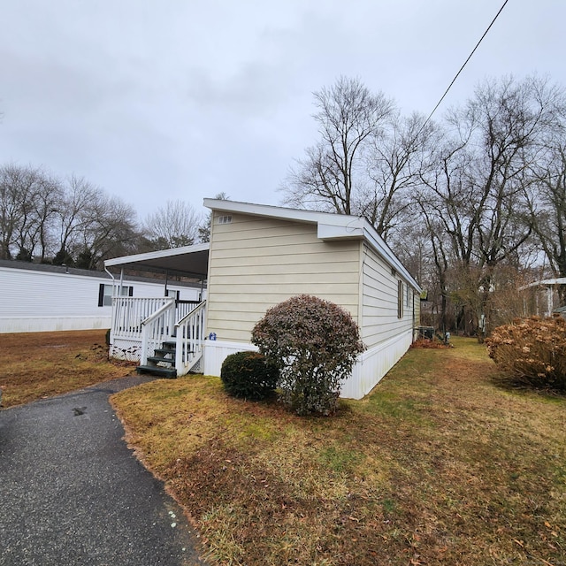 view of property exterior featuring a carport, covered porch, a lawn, and aphalt driveway