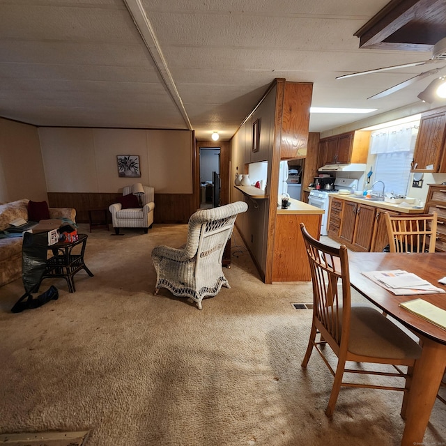 dining space with light carpet, wooden walls, and wainscoting