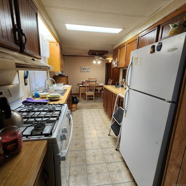 kitchen featuring ceiling fan, white appliances, and a sink