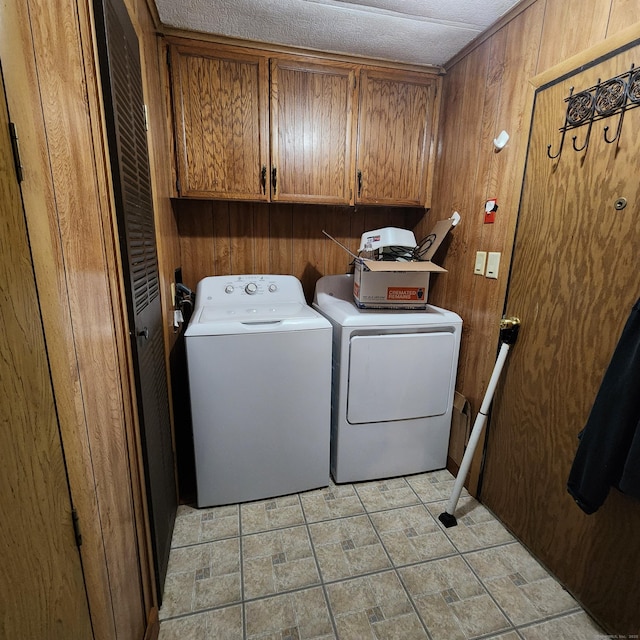 laundry room featuring washing machine and dryer, cabinet space, and wood walls