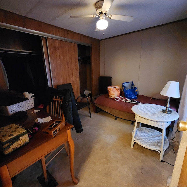 home office with wooden walls, light colored carpet, and a ceiling fan