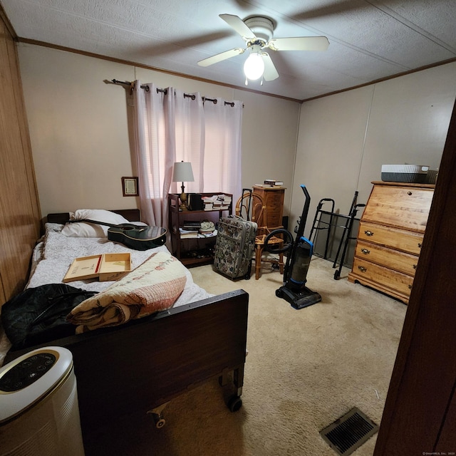 bedroom featuring visible vents, a textured ceiling, carpet floors, crown molding, and ceiling fan