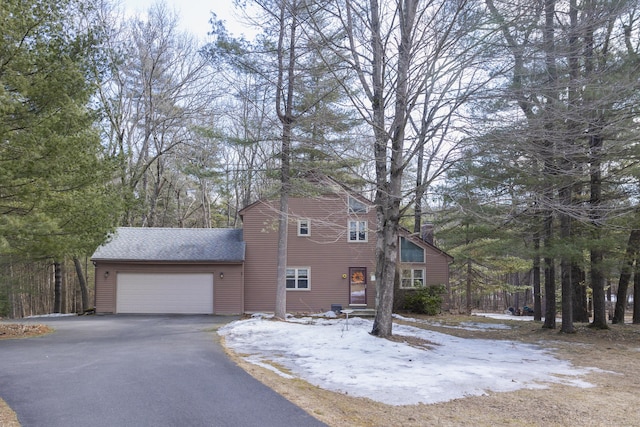 view of front of house with aphalt driveway, an attached garage, and roof with shingles