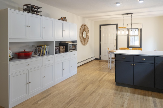 kitchen with light countertops, light wood-style floors, white cabinetry, decorative light fixtures, and baseboard heating