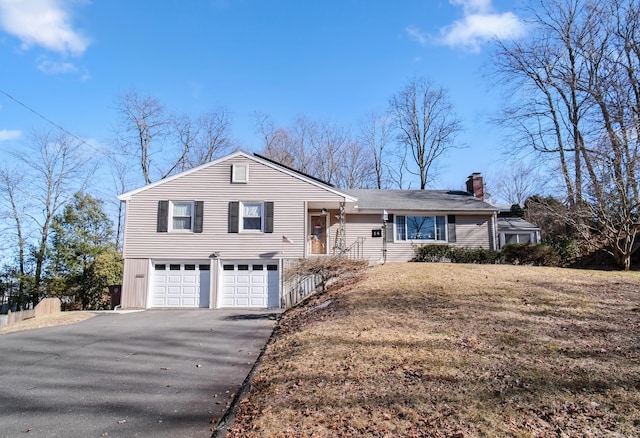 single story home with aphalt driveway, a chimney, and a garage