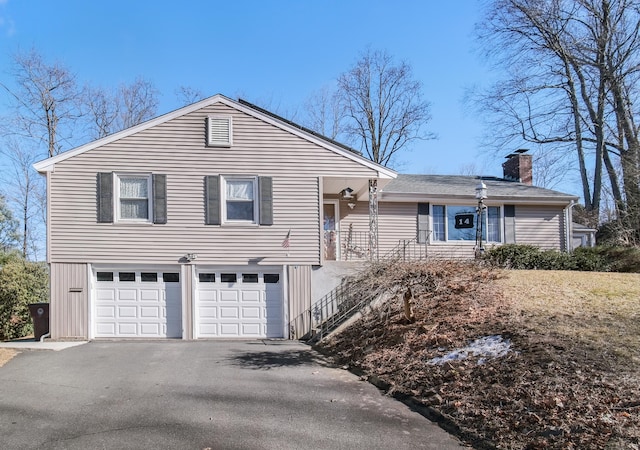 view of front of home with a garage, a chimney, and driveway