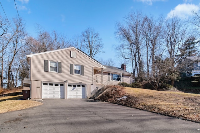 view of front facade featuring aphalt driveway, an attached garage, and a chimney