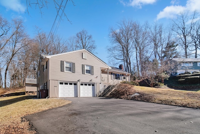 view of property exterior with driveway, a chimney, and an attached garage