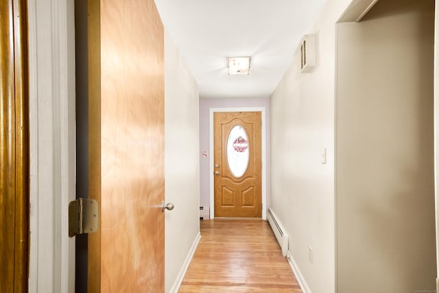 doorway featuring a baseboard heating unit, baseboards, and light wood-style floors