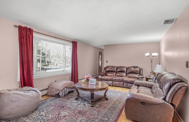 living room with wood finished floors, visible vents, and a baseboard radiator