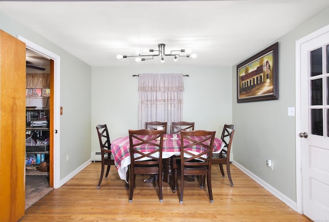 dining room with light wood finished floors, baseboards, and baseboard heating