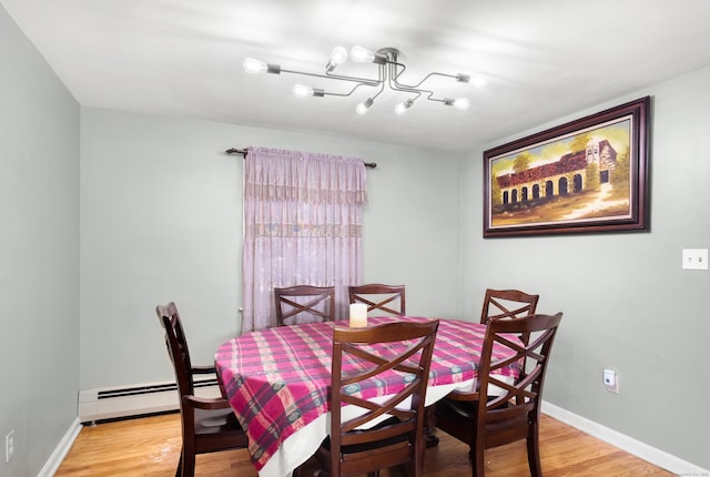 dining area with a baseboard radiator, baseboards, and wood finished floors