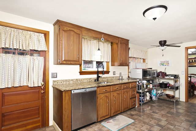 kitchen featuring ceiling fan, light stone counters, brown cabinets, appliances with stainless steel finishes, and a sink