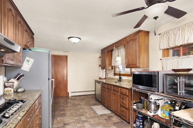 kitchen featuring a sink, stone finish flooring, light stone counters, appliances with stainless steel finishes, and a baseboard radiator