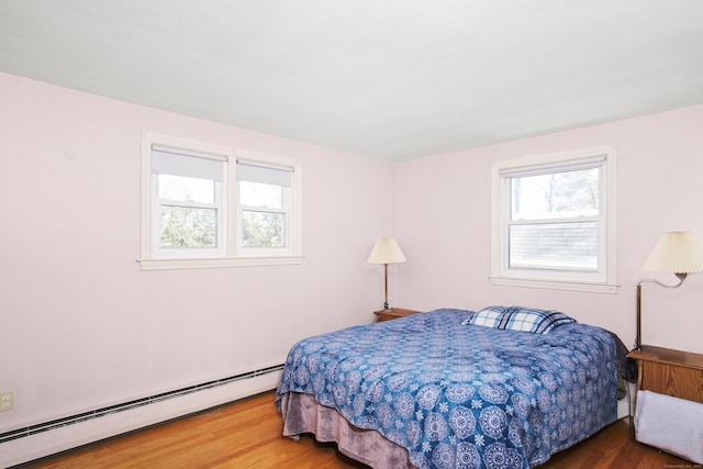 bedroom featuring baseboard heating and wood finished floors