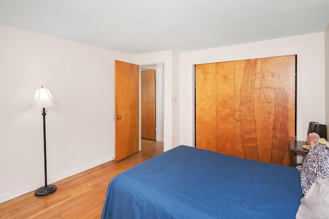 bedroom with a closet, baseboards, and wood finished floors