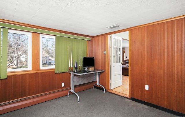 office area featuring carpet, visible vents, and wood walls