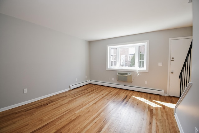 empty room with light wood finished floors, baseboards, stairs, baseboard heating, and a wall mounted AC