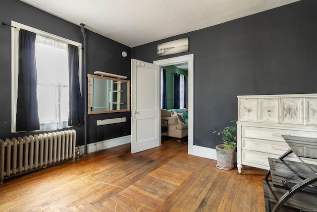 bedroom with baseboards, radiator heating unit, and hardwood / wood-style flooring