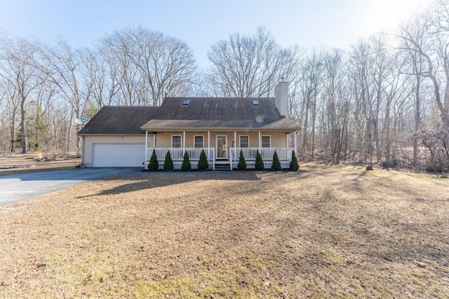 view of front of property featuring a garage, a chimney, a porch, and driveway