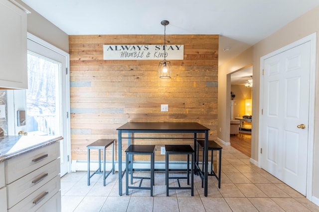 dining area featuring wooden walls, light tile patterned flooring, and baseboards