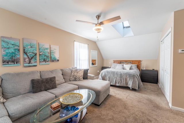 bedroom featuring light carpet, a ceiling fan, a closet, vaulted ceiling with skylight, and baseboards