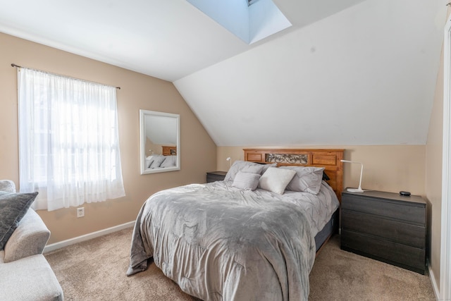 bedroom featuring baseboards, lofted ceiling with skylight, and light colored carpet