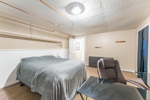 bedroom featuring wainscoting and a textured ceiling