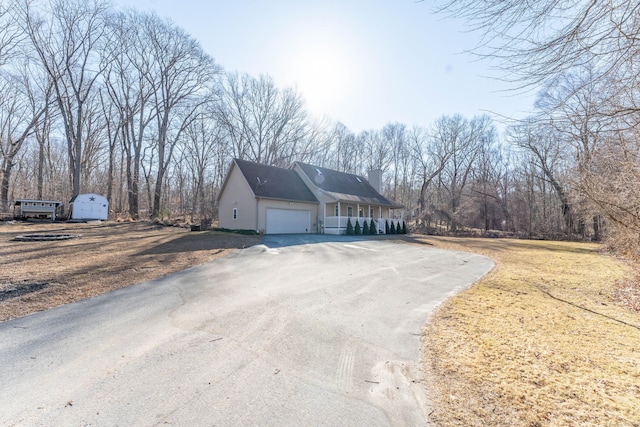 view of side of home featuring aphalt driveway, an attached garage, and a chimney